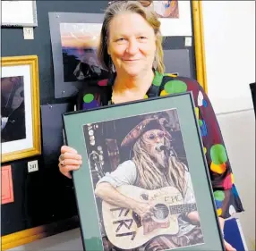  ??  ?? Double win for Jo Bryant — holding her photo that won second prize in the people section at ART Waikino. Her black and white photo behind of the little boy and violin won first prize.