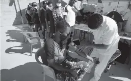  ?? FERNANDO LLANO AP ?? A doctor measures the blood pressure of Haitian migrants at a new refugee shelter in Ciudad Acuna, Mexico, on Saturday