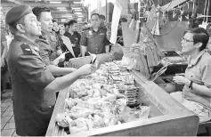  ??  ?? Azri (left) and Nukley (second left) checking the price of chicken at the central market yesterday.