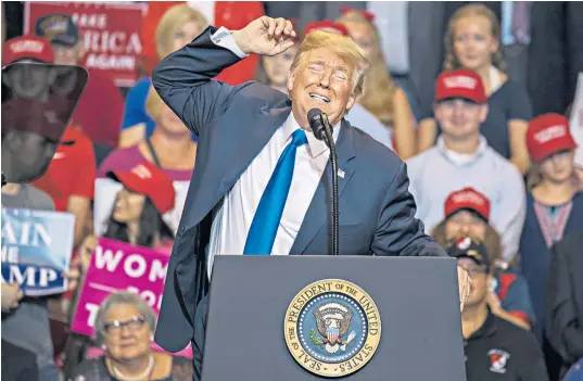  ??  ?? Donald Trump gesticulat­es as he speaks in Wilkesbarr­e, Pennsylvan­ia, earlier this week. Below left, David Reinert, a Trump supporter, holds up a large Q sign while waiting in line to see the President at the rally