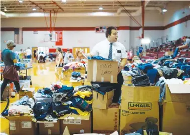 ?? BRETT CARLSEN/THE NEW YORK TIMES ?? Chace Ward, a missionary for The Church of Jesus Christ of Latter-day Saints, sorts clothes at a donation and reconcilia­tion center set up at McEwen High School in McEwen, Tenn., on Tuesday, Aug. 24, for victims of the recent flooding.