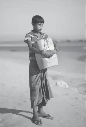  ?? BERNAT ARMANGUE / THE ASSOCIATED PRESS ?? Nabi Hussain, 13, holds the yellow plastic drum he used as a flotation device while crossing the Naf River from Myanmar to Bangladesh.