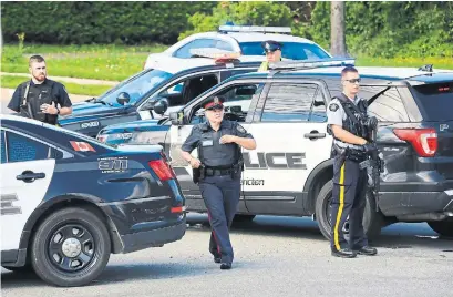  ?? KEITH MINCHIN/THE CANADIAN PRESS ?? Police and RCMP officers survey the scene of the shooting in Fredericto­n on Friday.