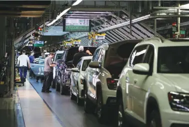  ?? STAFF FILE PHOTO ?? Volkswagen employees work around vehicles moving down the assembly line at the Chattanoog­a production plant.