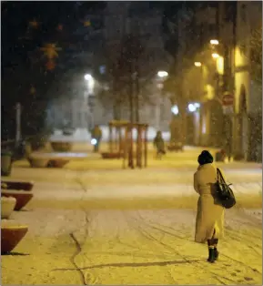  ?? The Associated Press ?? A woman walks during a snowfall after a curfew to prevent the spread of the coronaviru­s, in Strasbourg, eastern France, Thursday.