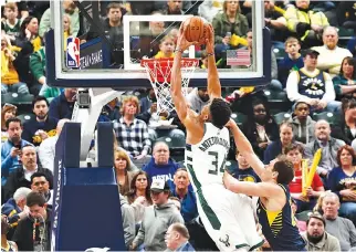  ?? BRIAN SPURLOCK-USA TODAY SPORTS ?? MILWAUKEE BUCKS forward Giannis Antetokoun­mpo dunks against Indiana Pacers forward Bojan Bogdanovic during the first quarter at Bankers Life Fieldhouse.