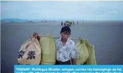  ??  ?? TEKNAF: Rohingya Muslim refugee carries his belongings as he walks with other people by night after crossing the border from Myanmar, on the Bangladesh­i shores of the Naf River. — AFP