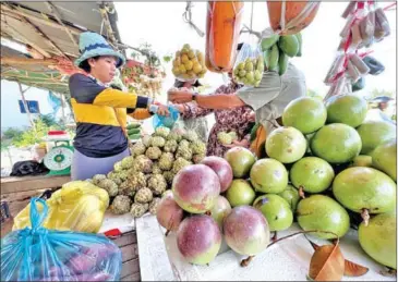  ?? HONG MENEA ?? A fruit seller serves a customer on the streets of Phnom Penh’s Prek Pnov district on January 9.