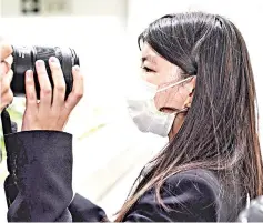  ?? — AFP photo ?? May-ling tries to block a photojourn­alist’s camera after testifying at the High Court during her father’s trial.