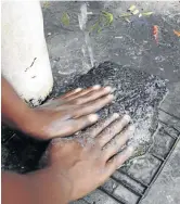  ?? / NEIL BAYNES ?? A man washes his hands under a tap after a cholera outbreak in the Western Cape.