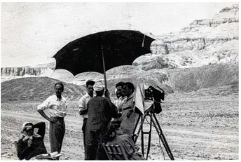  ??  ?? Marco de Gastyne, les mains sur les hanches, lors du tournage du film L’or des pharaons au pied de la pyramide de Saqqarha. (Collection Rebecca-Zabriel Toumarinso­n)