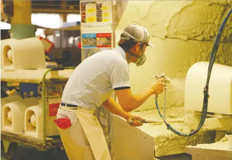  ?? SAKURA MURAKAMI/REUTERS ?? A worker sprays glaze onto a toilet at a Toto toilet factory in Kitakyushu, Japan. New western-style toilets are being installed in public facilities all over the country to prepare for the deluge of tourists expected to visit the country for the 2020 Olympics.