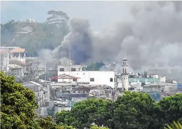  ?? Ted Aljibe / AFP / Getty Images ?? Smoke rises near a public market after military helicopter­s fire rockets on the positions of Muslim extremists in Marawi, Philippine­s. Military forces bombed residentia­l areas as they battled militants.