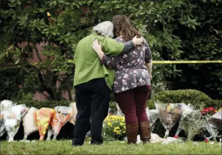  ?? MATT ROURKE — ASSOCIATED PRESS ?? Two people support each other in front of flowers at a makeshift memorial at the Tree of Life Synagogue in Pittsburgh, Sunday, Oct. 28, 2018. Robert Bowers, the suspect in Saturday’s mass shooting at the synagogue, expressed hatred of Jews during the rampage and told officers afterward that Jews were committing genocide and he wanted them all to die, according to charging documents made public Sunday.