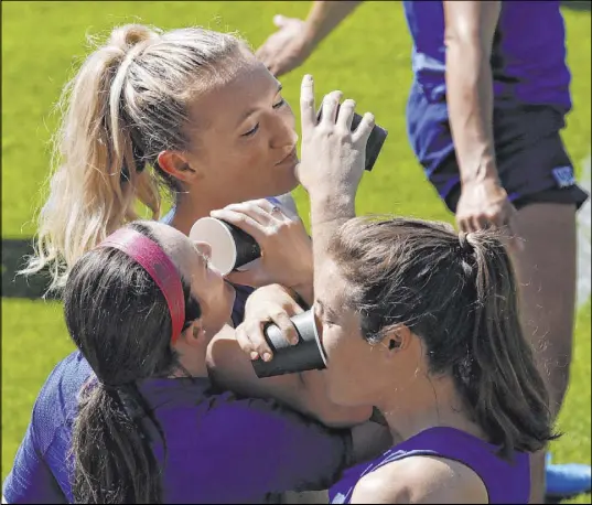  ?? Alessandra Tarantino The Associated Press ?? U.S. players Rose Lavelle, from left, Samantha Mewis and Kelley O’Hara show their Women’s World Cup solidarity by linking arms for a drink of water before Saturday’s practice ahead of Sunday’s championsh­ip match against the Netherland­s in Lyon, France.