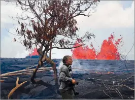  ?? AP PHOTO/JAE C. HONG ?? Photograph­er Carsten Peter, of Germany, watches Tuesday as lava erupt from fissures in the Leilani Estates subdivisio­n near Pahoa, Hawaii. Authoritie­s were racing Tuesday to close off production wells at a geothermal plant threatened by a lava flow...