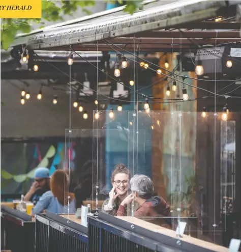  ?? DARRYL DYCK/THE CANADIAN PRESS ?? Patrons sit between Plexiglas barriers on the patio of a restaurant in Vancouver recently. Many Canadians are cautious about dining out, a survey finds.