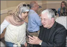  ??  ?? Eeem Musa (left) and Dr. Hank Siegelson look over phone images during a luncheon organized by a SyrianAmer­ican doctor and a decorated U.S. veteran.