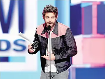  ??  ?? Thomas Rhett accepts the Male Artist of the Year award onstage.