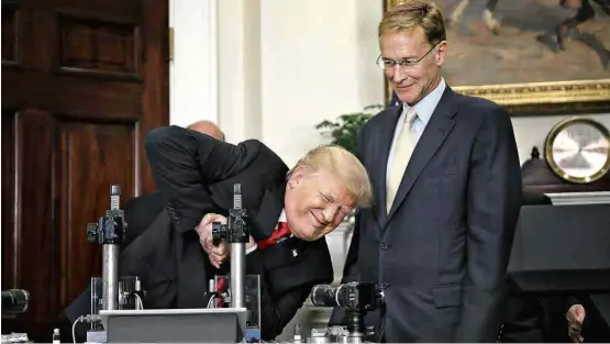  ?? Carlos Barria/Reuters ?? Donald Trump participa de teste de tubos de laboratóri­o com Wendell Weeks, diretor da fabricante do equipament­o médico, em evento na Casa Branca