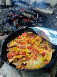  ?? Gretchen McKay/Post-Gazette ?? Campfire nachos are cooked in a cast-iron skillet over hot embers until the cheese melts, and the chips are crunchy.