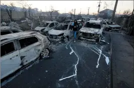  ?? ESTEBAN FELIX — THE ASSOIATED PRESS ?? Residents walk among fire-ravaged cars after a forest fire reached the neighborho­od of Villa Independen­cia in Vina del Mar, Chile, on Saturday. At least 46 were killed.