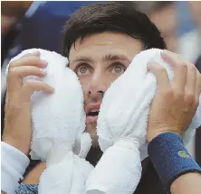  ?? AP PHOTO ?? IT’S A SCORCHER: Novak Djokovic uses towels filled with ice to cool himself during his four-set win against Marton Fucsovics at the U.S. Open yesterday.