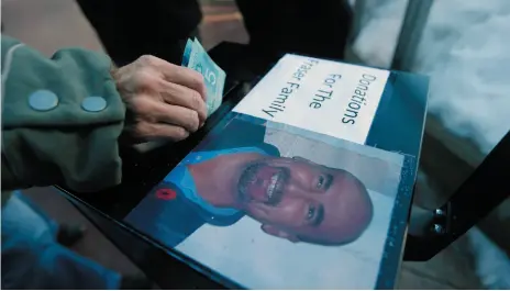  ?? CP PHOTO ?? A women places some money in a donation box as Winnipeg bus drivers gathered to support each other at a rally outside city hall in Winnipeg on Friday for Irvine Fraser, who was killed by a passenger.