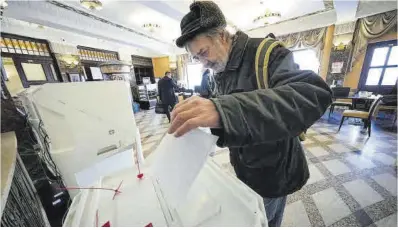  ?? Alexander Zemlianich­enk / AP ?? Un hombre deposita su voto en la urna, ayer en Moscú.
