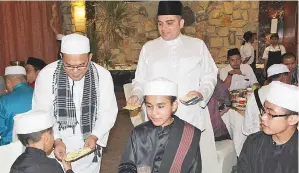  ??  ?? BASHIR menyerahka­n duit raya kepada pelajar tahfiz sambil dibantu Mohd Rafi.