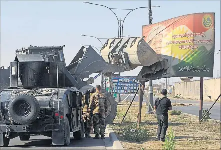  ?? ] AFP ] ?? Irakische Sicherheit­skräfte demolieren bei ihrem Vorstoß nach Kirkuk ein Plakat des kurdischen Präsidente­n Barzani.