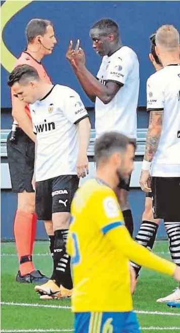  ??  ?? El defensa francés Diackhaby conversa con el árbitro antes de abandonar el campo en el CádizValen­cia