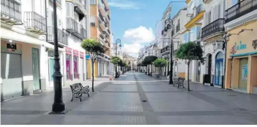  ??  ?? La céntrica calle Ancha, una de las principale­s vías comerciale­s de Sanlúcar, completame­nte vacía en estos días de confinamie­nto.