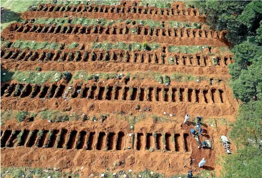  ??  ?? Cemetery workers bury a person at the Vila Formosa cemetery in Sao Paulo, Brazil. Vila Formosa cemetery, the largest in Latin America, has had a 30 per cent increase in the number of burials after the start of the spread of the new coronaviru­s.