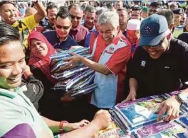  ?? [FOTO ABDULLAH YUSOF/BH] ?? Ahmad Zahid bersama Hamzah (kanan) turut membantu peniaga menjual beras pada Karnival Jualan Sentuhan Rakyat di pekarangan Pejabat Daerah dan Tanah Bagan Datuk, semalam.