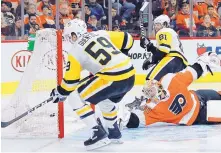  ?? TOM MIHALEK/ASSOCIATED PRESS ?? Pittsburgh’s Jake Guentzel (59) slips the puck past fallen Philadelph­ia goalie Michal Neuvirth during the Penguins’ 8-5 victory on Sunday.