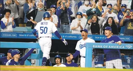  ?? Robert Gauthier Los Angeles Times ?? DODGERS MANAGER Dave Roberts, middle, is pumped up as Mookie Betts returns to the dugout after blasting a solo home run in the third inning Monday night. The Dodgers hit four homers off Atlanta Braves starter Drew Smyly during their 5-3 victory.