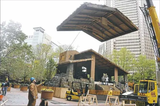  ?? Darrell Sapp/Post-Gazette ?? Workers on Thursday guide a section of the roof into place for a creche display at the U.S. Steel Plaza in Downtown. The display will be ready for Comcast Light Up Night on Nov. 16, a celebratio­n that kicks off the holiday season in Pittsburgh.