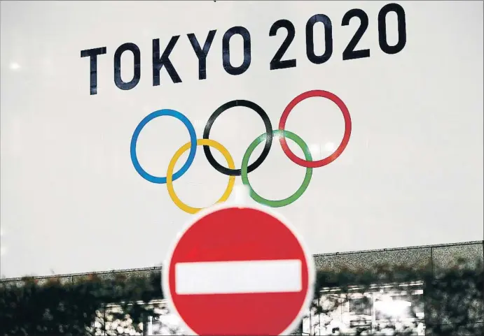  ?? ISSEI KATO / REUTERS ?? LOS EFECTOS DEL CORONAVIRU­S EN EL DEPORTE
Una señal de dirección prohibida frente a un cartel de los Juegos de Tokio 2020