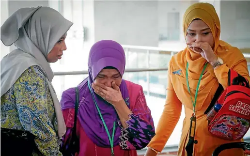  ?? AP ?? Sarah Nor, centre, the mother of Norliakmar Hamid, a passenger on the missing Malaysia Airlines Flight 370, cries after she listened to an investigat­ion report on missing Flight 370, in Putrajaya, Malaysia.