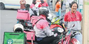  ?? SOMCHAI POOMLARD ?? Online food delivery drivers have seen increased food delivery orders amid the surge in Covid-19 cases across the country.