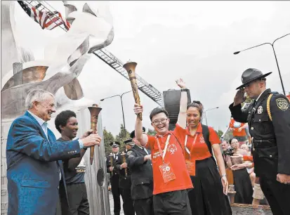  ?? ABEL URIBE/CHICAGO TRIBUNE ?? Richard LaMunyon, left, founder of the Law Enforcemen­t Torch Run for Special Olympics, and Loretta Claiborne light seven torches symbolizin­g the seven regions taking part in the Special Olympics 50th Anniversar­y ceremonies outside Soldier Field in July 2018.