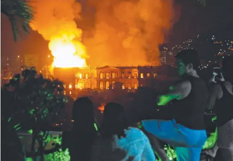  ?? Picture: AFP ?? HISTORY UP IN FLAMES: People watch as a fire engulfs the National Museum in Rio de Janeiro, Brazil.