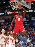  ?? AP PHOTO / GERALD HERBERT ?? New Orleans Pelicans guard Jrue Holiday (11) dunks over Chicago Bulls forwards Bobby Portis (5) and Jabari Parker (2) during the first half of an NBA basketball game in New Orleans, Wednesday.