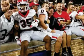 ?? JOSHUA L. JONES / ATHENS BANNER-HERALD ?? Georgia players, including freshman quarterbac­k Josh Fromm (11), celebrate with fans after their signature win over Notre Dame on Sept. 9.
