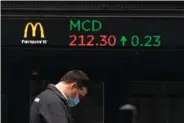  ?? AP PHOTO BY MARK LENNIHAN ?? A man walks by a stock ticker displaying the cost of McDonald’s shares at the New York Stock Exchange on Feb. 23. On Wednesday, President Joe Biden proposed doubling the tax rate that the highest-earning Americans pay on profits made from stocks and other investment­s.