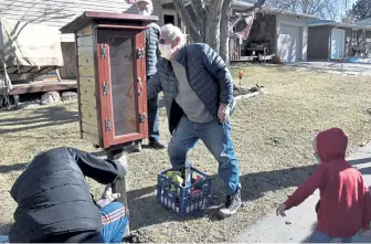  ?? Kelsey Hammon, Times-Call ?? Russ Schnell, right, works to install his 45th Little Free Library on Jan. 16 in front of a Longmont home. Mark Lareau helps with the installati­on while 3-year-old Ellis Miller watches.