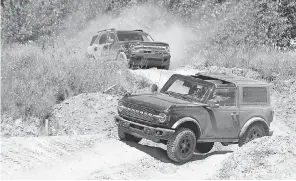  ?? ERIC SEALS/ USA TODAY NETWORK ?? A 2021 Ford Bronco four- door follows a Bronco two- door around the course during the 2020 Bronco Day event at the soon- to- be- opening Holly Oaks Off- road Park in Holly, Mich.