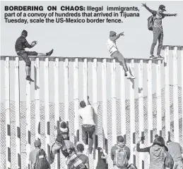  ??  ?? BORDERING ON CHAOS: Illegal immigrants, part of a convoy of hundreds that arrived in Tijuana Tuesday, scale the US-Mexico border fence.