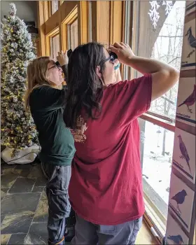  ?? RENEE BORCAS — THE NEWS-HERALD ?? Geauga Park District volunteers Amber Weinrich (left) and Heather Beukeman look for birds during the Great Backyard Bird Count at The West Woods on Feb. 16.